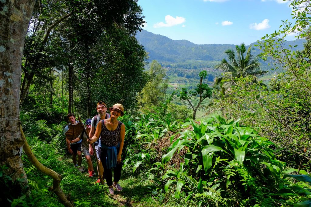 A group of tourists enjoying trekking in Sidemen in Bali through pristine nature and jungle from our holiday villa in Bali.