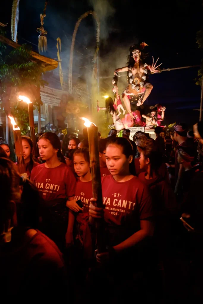 Balinese women carrying torches, walking in front of the Ogoh Ogoh monster during the parade the night before Nyepi day.